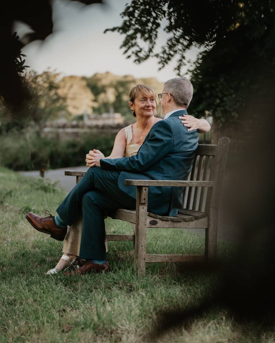 Cotswold stone cottages behind a wedding couple in Swinbrook